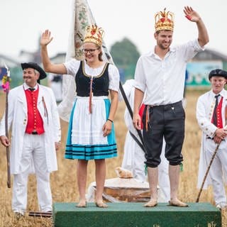 Die Sieger des Schäferlaufs, Königin Sophia und König Moritz, stehen mit matschigen Füßen auf dem Siegerpodest und winken
