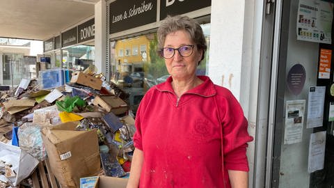 Monika Baumgarten steht vor einem Berg verschlammter Bücher vor dem Buchladen - nach der Flut in Rudersberg. 