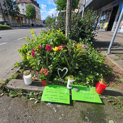 Blumen und Grablichter liegen und stehen an der Stelle in der Bahnhofstraße in Nürtingen, wo am Sonntag zwei Menschen bei einem Unfall ums Leben gekommen sind.