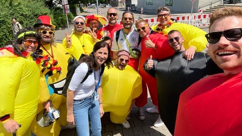 Deutsche Fans in witziger Schwarz-Rot-Gold-Klamotte und SWR-Reporterin Nicole Freyler lassen sich ablichten am Stadtgarten Stuttgart vor dem zweiter "Heimspiel" der Deutschen gegen Ungarn bei der EURO 2024.