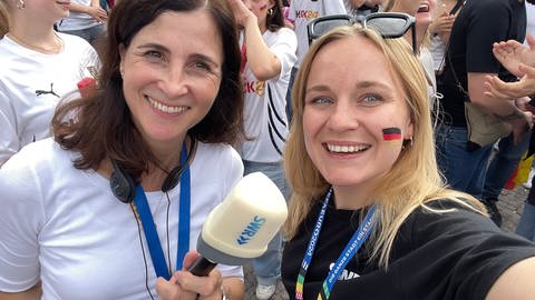 Die SWR-Reporterinnen Nicole Freyler und Anna Knake tummeln sich in der Menge beim Public Viewing in Stuttgart auf dem Schlossplatz.