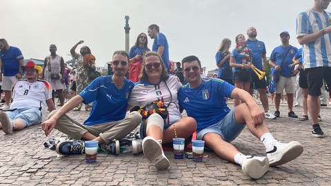 EURO 2024 Achtelfinale Schweiz-Italien: Justin, Anna-Maria und Toni (von links) haben es sich schon beim Public Viewing auf dem Schlossplatz Stuttgart vor der Leinwand bequem gemacht: Sie fiebern ab 18 Uhr mit der italienischen Mannschaft mit. 