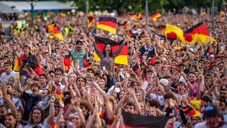 Fußballfans mit Deutschland-Flaggen und Bemalung feiern beim Public Viewing auf dem Stuttgarter Schlossplatz.