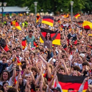 Fußballfans mit Deutschland-Flaggen und Bemalung feiern beim Public Viewing auf dem Stuttgarter Schlossplatz.