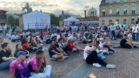 Im Sitzen und ganz entspannt verfolgenen die Leute das Viertelfinale Frankreich gegen Portugal beim Public Viewing auf dem Schlossplatz Stuttgart.