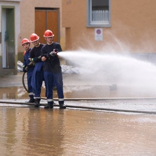 Drei Kinder der Jugendfeuerwehr löschen gemeinsam mit Wasser.