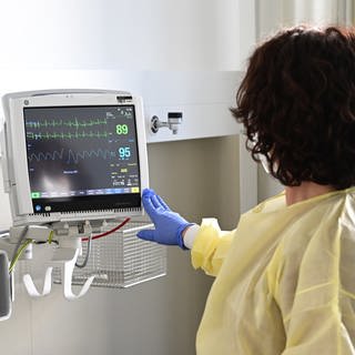 Eine Pflegerin schaut in einem Krankenzimmer im Klinikum Stuttgart auf einen Monitor einer Patientin