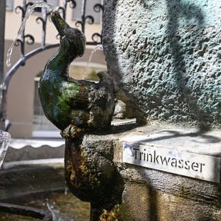 Am Hans-Im-Glück-Trinkwasserbrunnen in der Stuttgarter Innenstadt wird ein Glas Wasser mit Trinkwasser gefüllt.