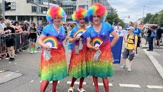 Ein Trio in regenbogenbuntposiert bei der CSD-Parade durch  Stuttgart.