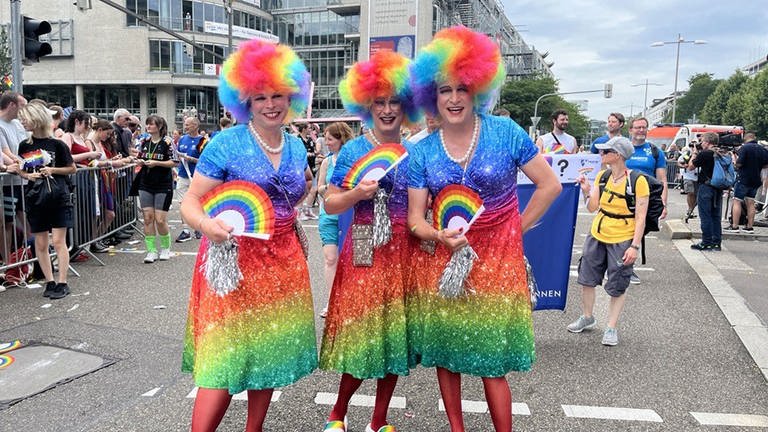Ein Trio in regenbogenbunt posiert bei der CSD-Parade durch  Stuttgart.