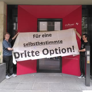 Zwei Personen halten ein Banner mit der Aufschrift "Für eine selbstbestimmte dritte Option"