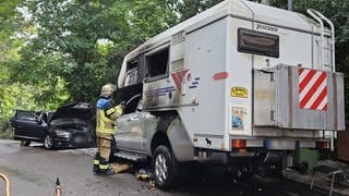 Zwei verbrannte geparkte Autos stehen in Stuttgart Ost am Straßenrand, ein Feuerwehrmann inspiziert das eine Wrack: Wohl ein Serientäter hat in Stuttgart an drei Tagen infolge mehrere Autos in Brand gesetzt.