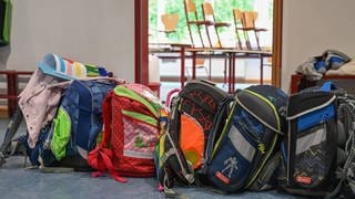 Rucksäcke von Kindern vor einem Klassenzimmer in einer Grundschule