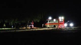 Rettungskräfte stehen in der Nacht an einem Baum.