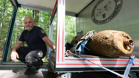 Christoph Rottner von der Kampfmittelbeseitigung kniet nach einer Entschärfung einer Weltkriegsbombe in Feuerbach neben der Bombe in einem Fahrzeug.