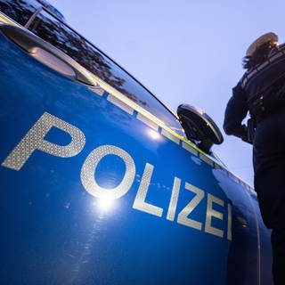 Eine Polizistin steht neben ihrem Einsatzwagen.