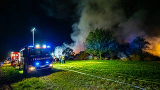 Auf einer Wiese bei Unterensingen im Kreis Esslingen brennen Strohballen lichterloh. Einsatzkräfte der Feuerwehr versuchen den Brand einzudämmen.