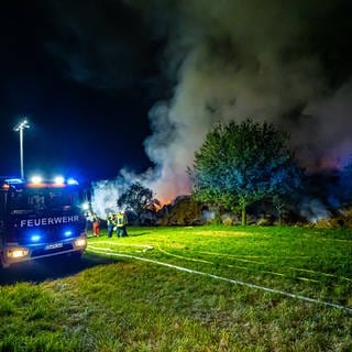 Auf einer Wiese bei Unterensingen im Kreis Esslingen brennen Strohballen lichterloh. Einsatzkräfte der Feuerwehr versuchen den Brand einzudämmen.