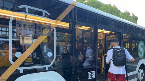 Mann mit Roller steigt in einen Bus