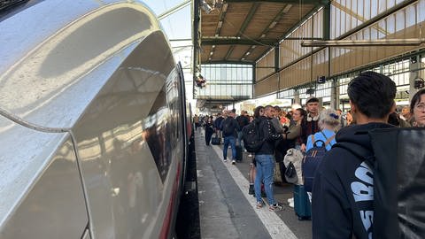 Menschen stehen im Stuttgarter Hauptbahnhof am Gleis und warten, weil ihre Züge sich verspäten oder ausfallen. 