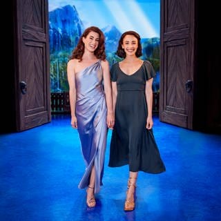 Ann Sophie und Abla Alaoui stehen vor der Kulisse des Disney-Musicals "Die Eiskönigin" in Stuttgart.