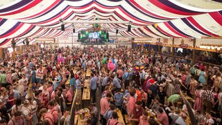 Feiernde Menschenmassen in einem Festzelt auf dem Cannstatter Wasen in Stuttgart 