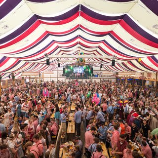 Feiernde Menschenmassen in einem Festzelt auf dem Cannstatter Wasen in Stuttgart 