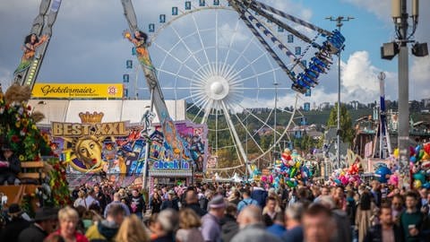 Besucher des 177. Cannstatter Volksfests gehen über den Cannstatter Wasen.