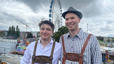 Will und George stehen vor dem Gelände des 177. Cannstatter Volksfest auf dem Wasen in Stuttgart-Bad Cannstatt. Die Briten sind mit Freunden für das Event nach Deutschland gekommen.