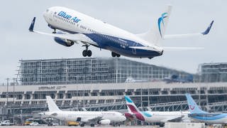 Ein Flugzeugt hebt am Flughafen Stuttgart ab. Im Hintergrund sieht man das Flughafengebäude für die Passagierabfertigung.