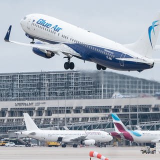 Ein Flugzeugt hebt am Flughafen Stuttgart ab. Im Hintergrund sieht man das Flughafengebäude für die Passagierabfertigung.