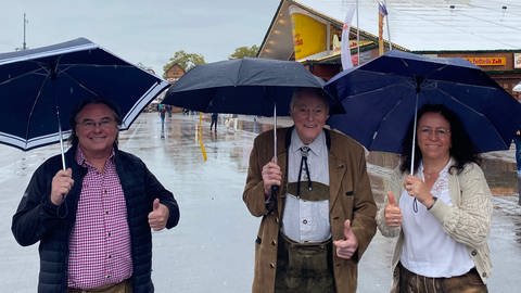 Lassen sich vom Regenwetter nicht die Laune verderben: Jürgen, Ernst und Renate (v.li.). Sie wollen im Festzelt Haxe essen gehen und später noch ein Bier trinken. 