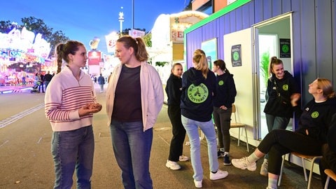 Archivfoto: Zwei Frauen stehen bei der "Wasenbojen" Anlaufstelle auf dem Volksfest Gelände.