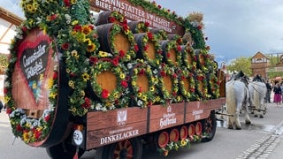 Auf dem Bild ist eine Kutsche mit vielen Bierfässern zu sehen, die von mehreren Pferden gezogen wird.