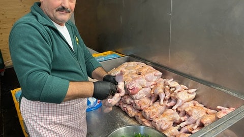 Ein Göckelesmaier-Mitarbeiter würzt im Festzelt auf dem Cannstatter Wasen Hühnchen. 