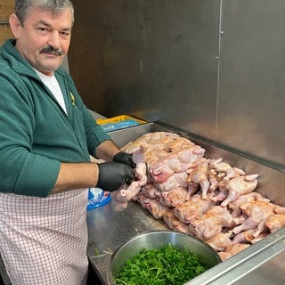 Ein Göckelesmaier-Mitarbeiter würzt im Festzelt auf dem Cannstatter Wasen Hühnchen. 