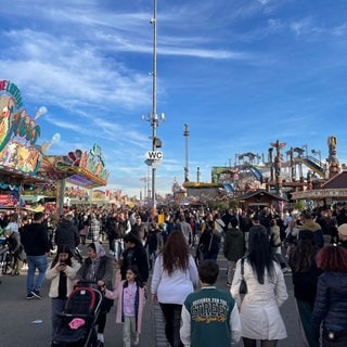 Das Bild zeigt Besucherinnen und Besucher des Cannstatter Volksfests 2024 auf dem Wasen.