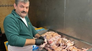 Ein Göckelesmaier-Mitarbeiter würzt im Festzelt auf dem Cannstatter Wasen Hühnchen. 