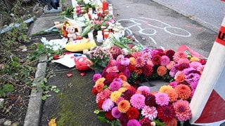 Blumen und Kerzen an einem Unfallort in Esslingen, an dem drei Menschen starben.