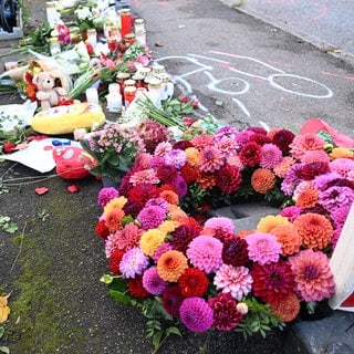 Blumen und Kerzen an einem Unfallort in Esslingen, an dem drei Menschen starben.