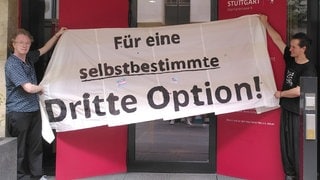 Zwei Personen halten ein Banner mit der Aufschrift "Für eine selbstbestimmte dritte Option"