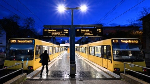 Eine Person geht in der Morgendämmerung an einer Stadtbahnhaltestelle zu einer Stadtbahn (Symbolfoto). 