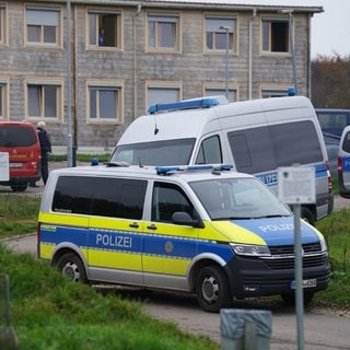 Zwei Streifenwagen der Polizei stehen vor einer Asylunterkunft in Hochdorf (Kreis Esslingen).