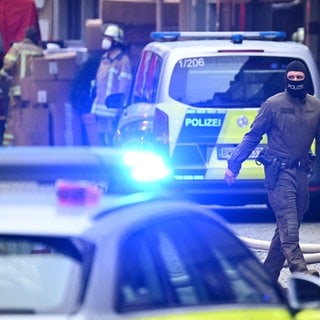 Ein Polizist mit Sturmhaube geht durch die Esslinger Innenstadt, wo am Donnerstag ein Mann einen anderen und sich selbst getötet haben soll.