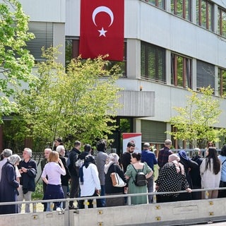 Wahlberechtigte Türkinnen und Türken stehen in Stuttgart vor einem Wahllokal zur Abstimmung für die Türkei-Wahlen.