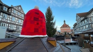 Eine rote Nikolausmütze aus Stoff ziert während der Adventszeit den Brunnen auf dem Marktplatz in Schorndorf beim Weihnachtsmarkt 2024.