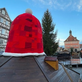 Eine rote Nikolausmütze aus Stoff ziert während der Adventszeit den Brunnen auf dem Marktplatz in Schorndorf beim Weihnachtsmarkt 2024.