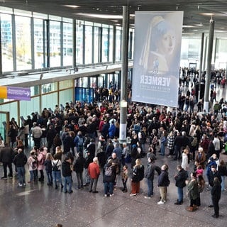 Auf dem Messegelände in Stuttgart warten viele Menschen vor den Ticketschaltern. 