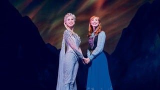 Anna und Elsa stehen im Musical "Die Eiskönigin" in Stuttgart nebeneinander auf der Bühne.