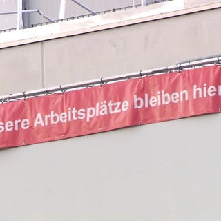 Auf einem Protestbanner, das an einem Bosch-Firmengebäude hängt, steht "Unsere Arbeitsplätze bleiben hier".